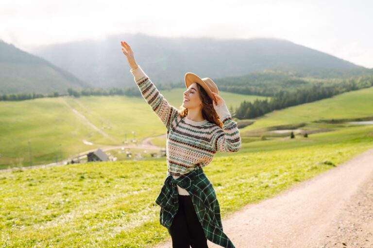 Happy female traveler exploring area in green valley with mountains in background. Concept of nature